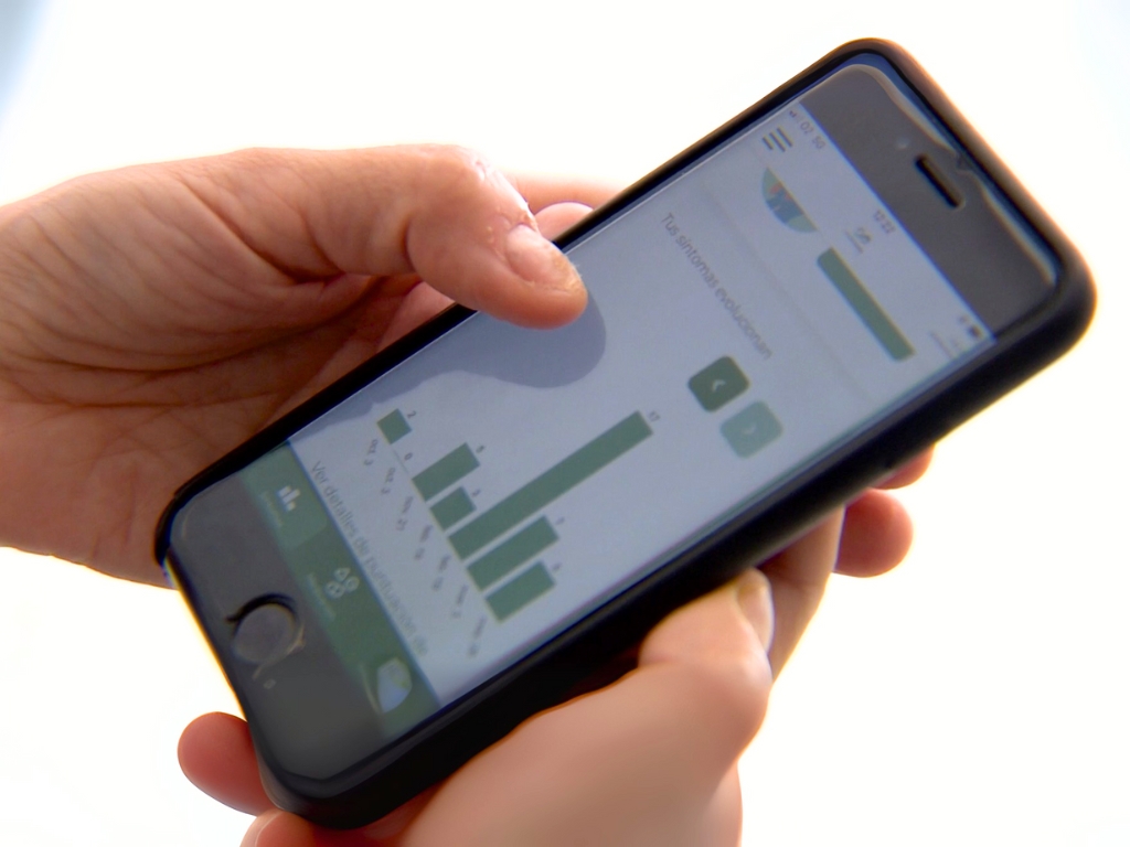 Manos sujetan teléfono móvil con app que muestra una estadística